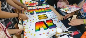 Young people decorate posters for Pride Month at The Wave Clinic.