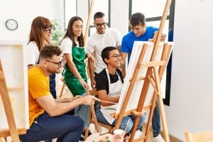 Group of young people surround a canvas painting.