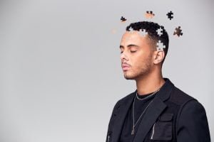 Young man with puzzle pieces coming out of his head.