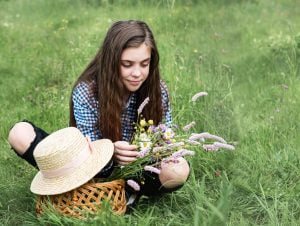 Girl in a summer field with a straw hat and a basket with flowers