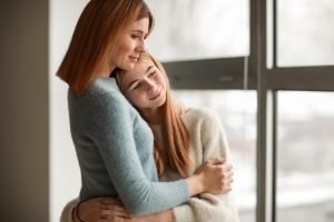 Portrait of happy mother and daughter near window