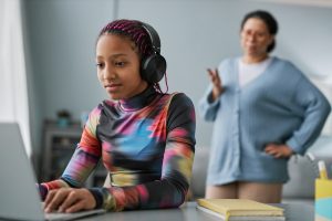 Young teen using computer with image of mother in the background