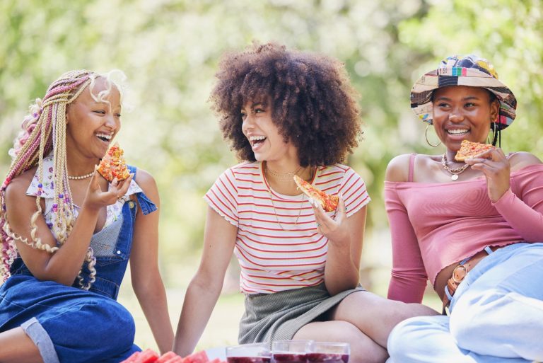 Friends picnic in park, people happy on holiday in New York summer and eating pizza outdoor