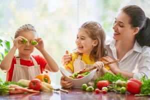 Healthy food at home. Happy family in the kitchen. Mother and children daughters are preparing the vegetables.