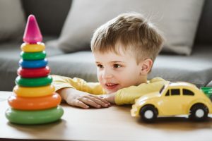 young boy playing with colorful toy car and puzzles