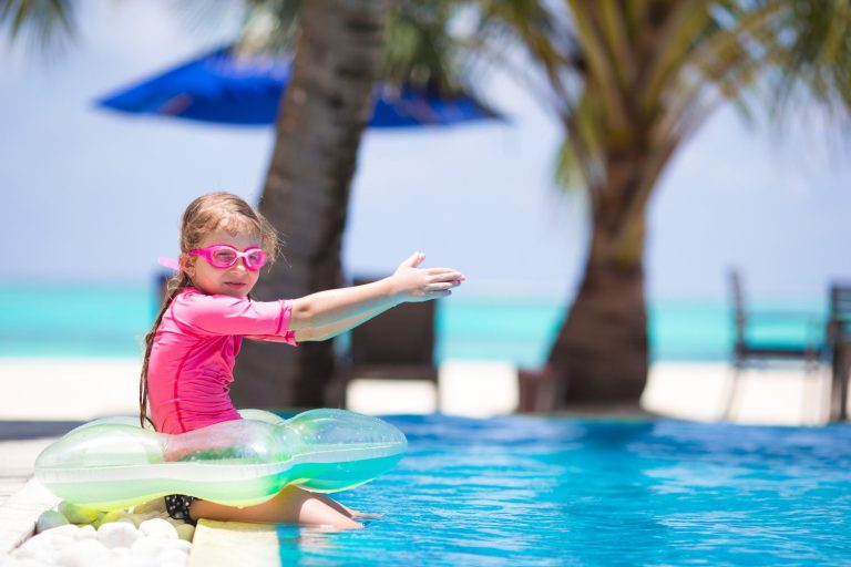 Smiling toddler girl playing in outdoor swimming pool