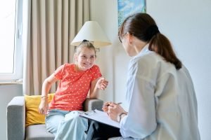 young girl smiling while talking to a therapist