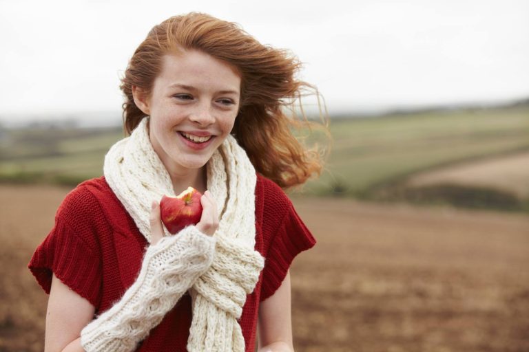 Teenage girl eating apple in field