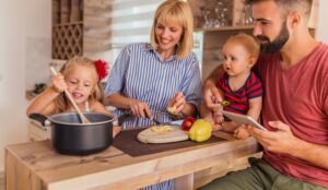 Beautiful happy family having fun cooking lunch together, sitting at kitchen counter and enjoying leisure time at home