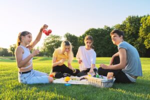 Teenagers having fun on a picnic in the park on lawn