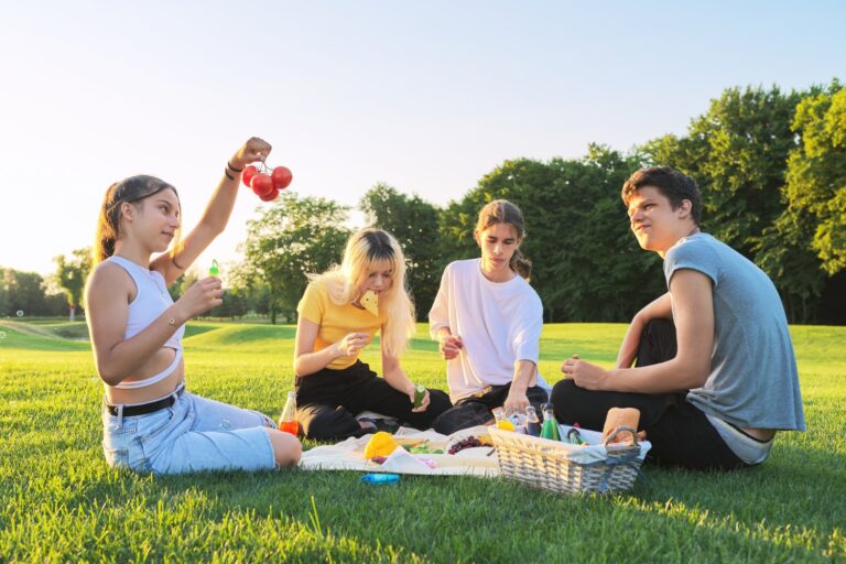 Teenagers having fun on a picnic in the park on lawn