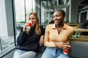 Two young women friends enjoying coffee together in a coffee shop close up