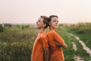 Funny twin brother boys playing outdoors on field at sunset