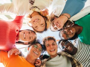 Low angle view of a group of multiracial friends standing on a circle, smiling and embracing