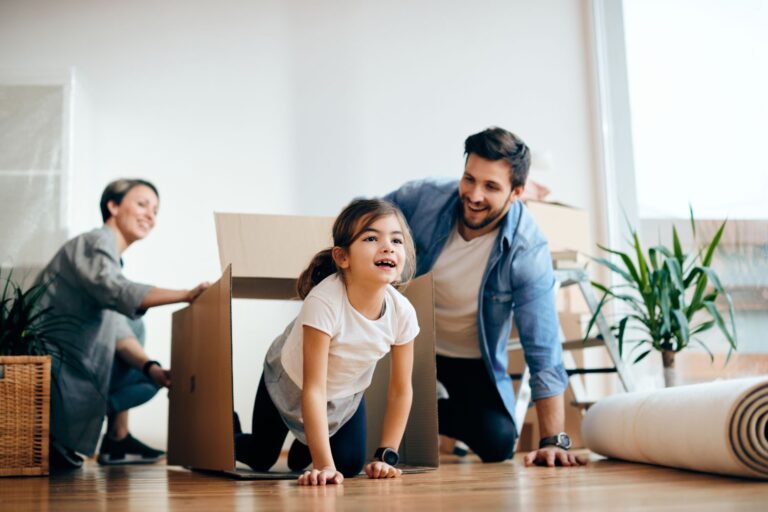 Playful family having fun with carton boxes while relocating into a new home. Focus is on daughter.