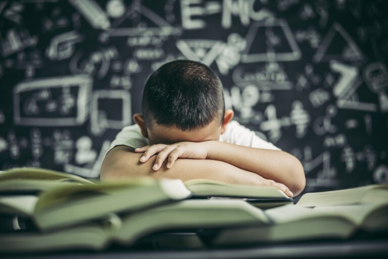A boy with glasses studying and drowsy.