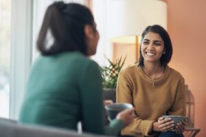 Shot of two young women drinking coffee while sitting together at home