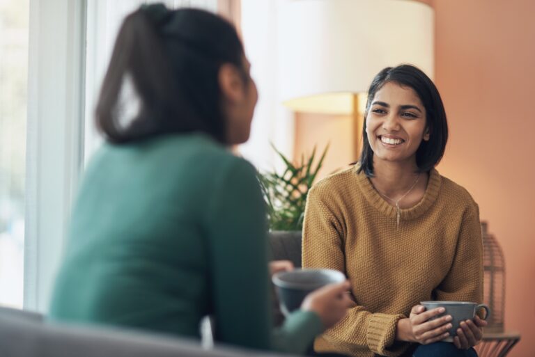 Shot of two young women drinking coffee while sitting together at home