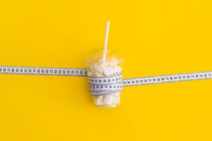 Image of a food cup wrapped with measuring tape symbolizing diet concept. Diet Products in Eating Di