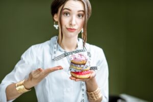 young woman holding donuts wrapped in measuring tape showing concept of eating disorder