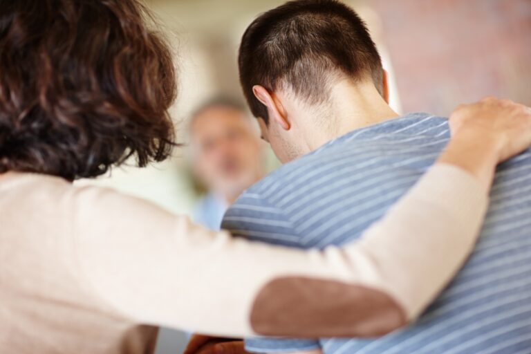 back shot of a mother hugging her teenage son, concept of teenage counseling and therapy